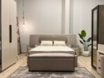غرفة نوم نيو مانشو ماستر بتصميم عصري فاخر من الخشب الطبيعي مع دولاب وتسريحة ومرايا بانورامية.